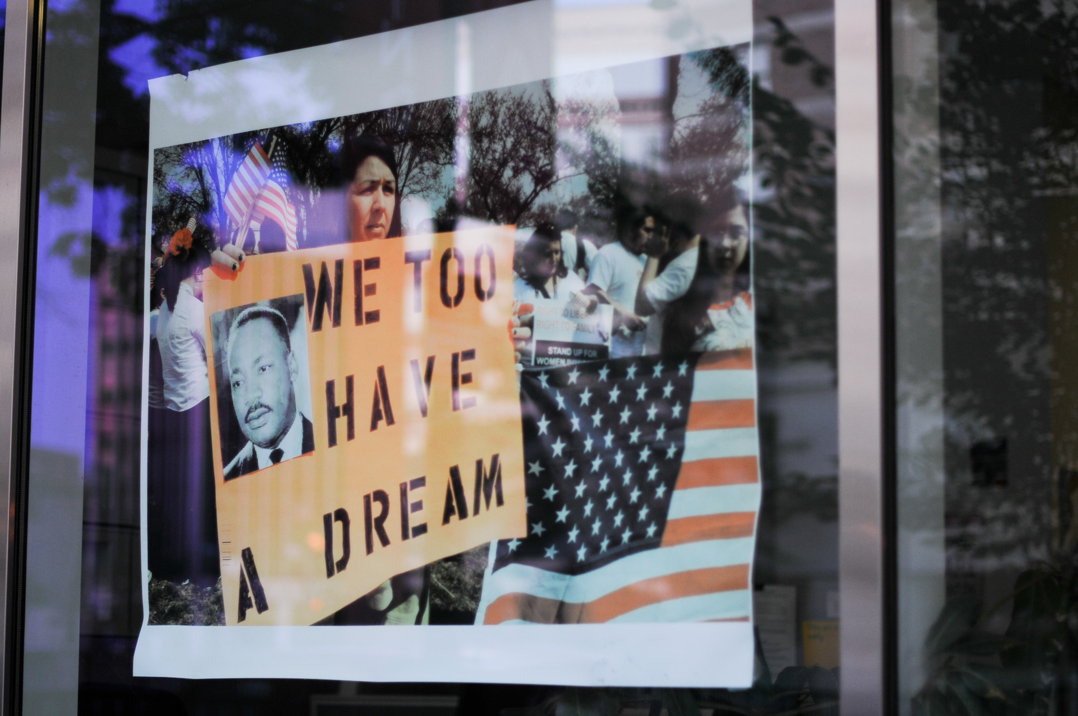 Washington, USA - July 8, 2011: The reflaction of demonstrators on a window shop. Woman carrying a pancart with the image of Dr. King and the slogan "We Too Have a Dream" in reference to woman and Litino rights.